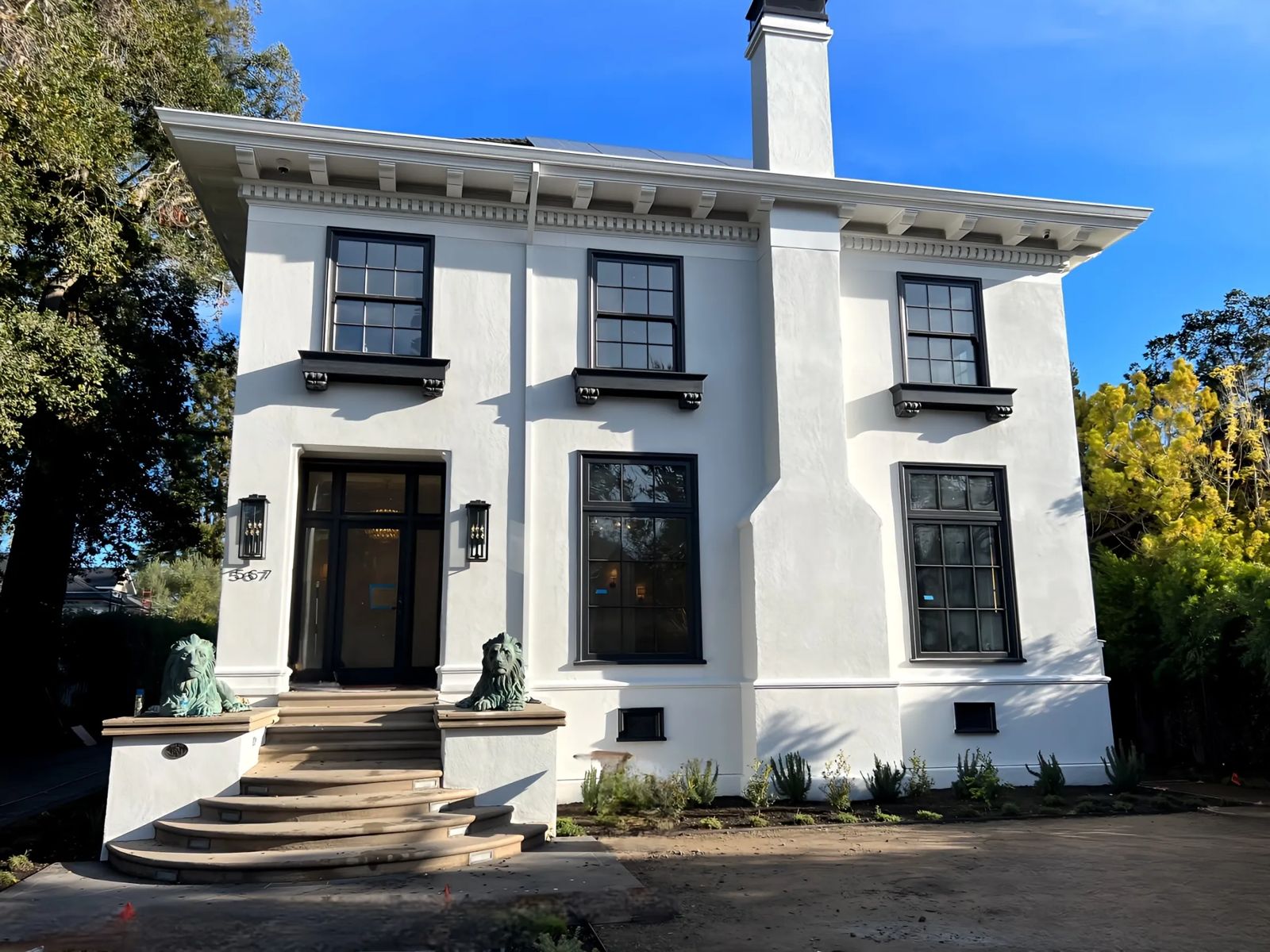Stucco home with dark window trim and stone entry steps