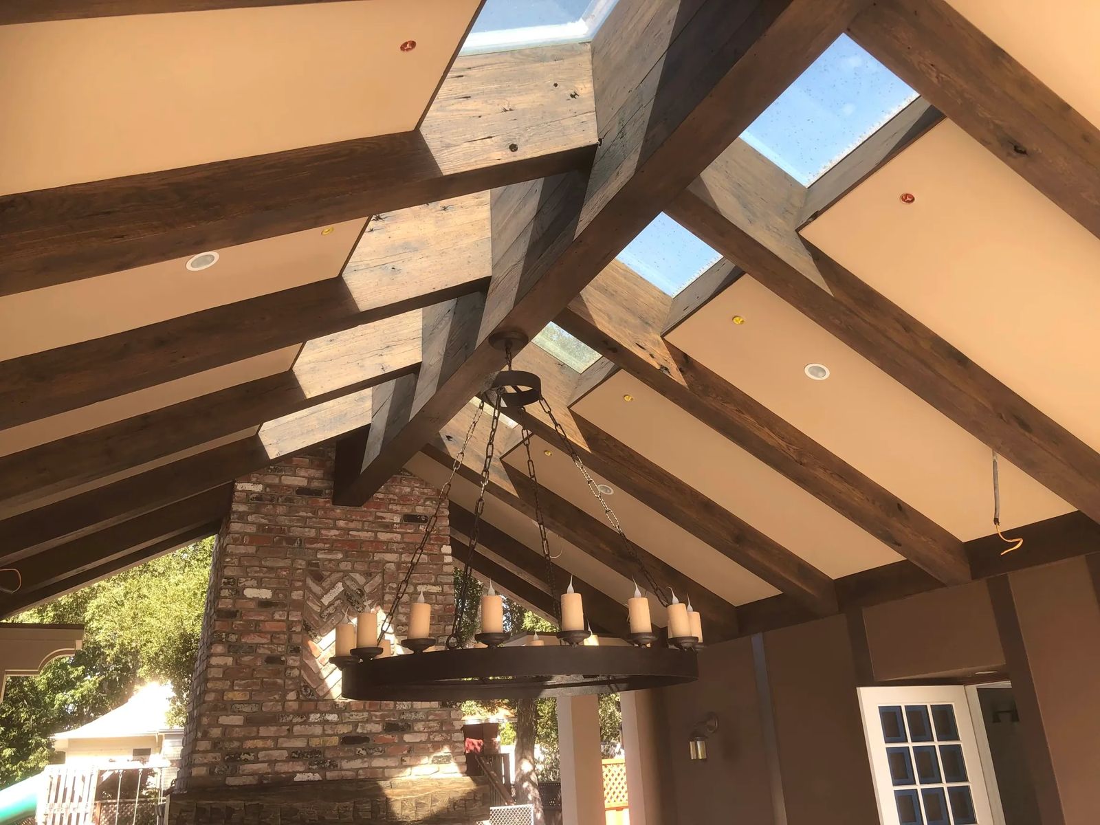 Covered patio with exposed beams, skylights, and brick fireplace